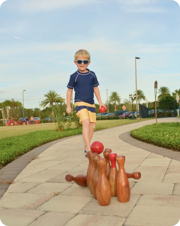 Boy playing lawn bowling on a walking path at Revelry